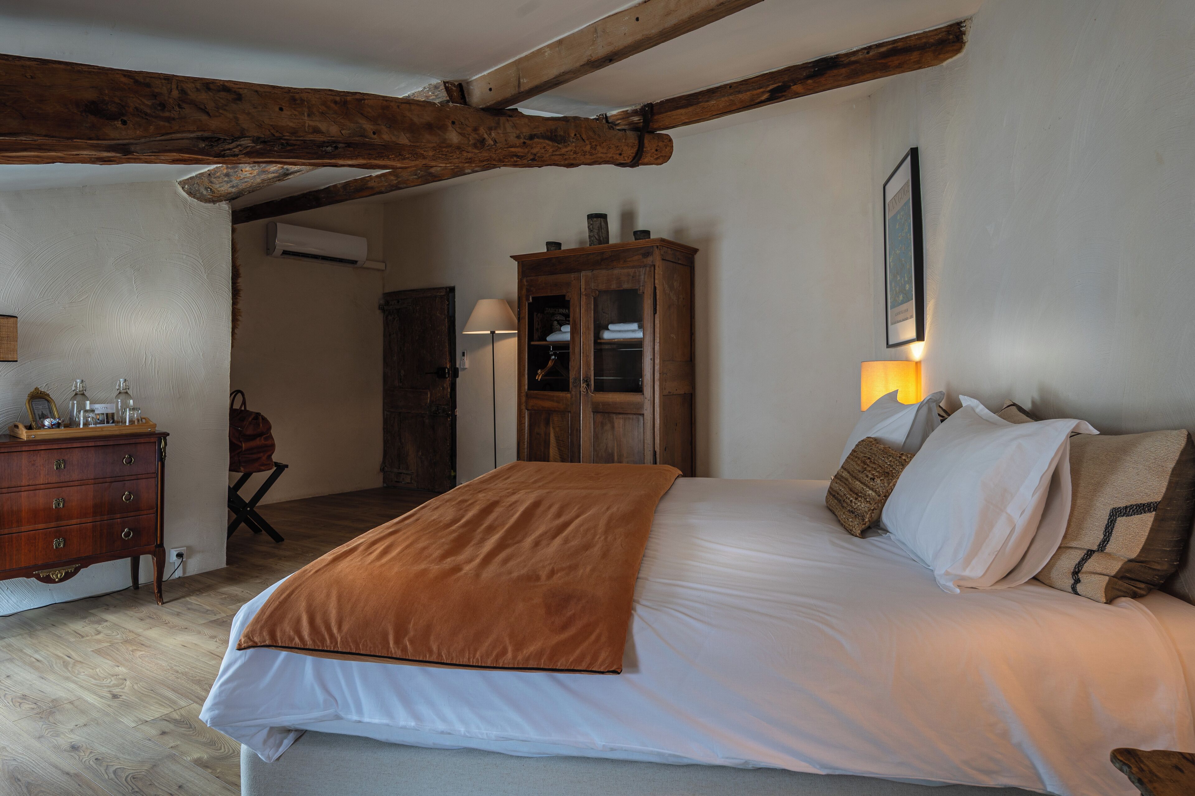 Un dormitorio con una cama grande, un armario de madera y una lámpara.