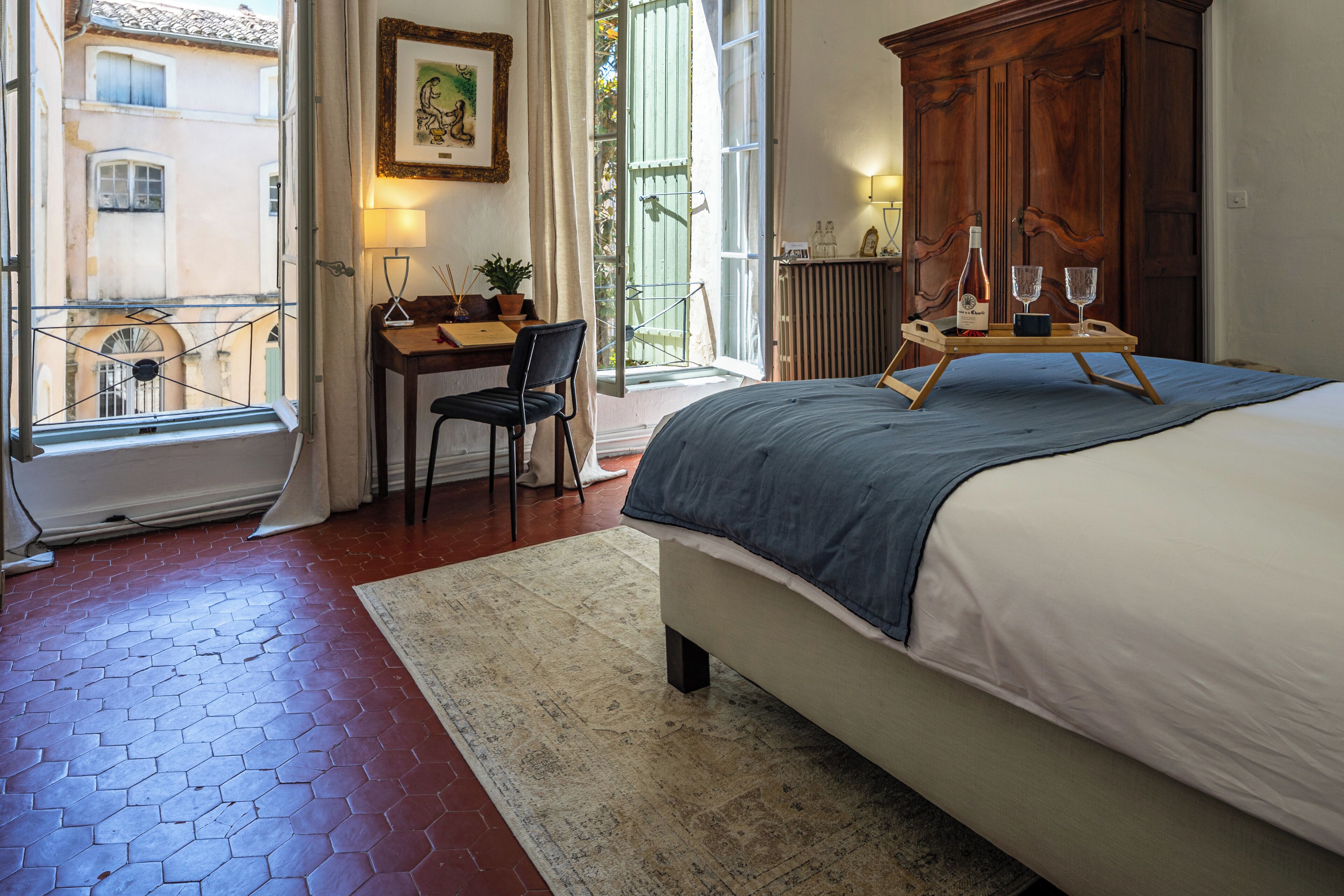 A bedroom with a bed, a desk with a chair, a radiator, and a wooden wardrobe.