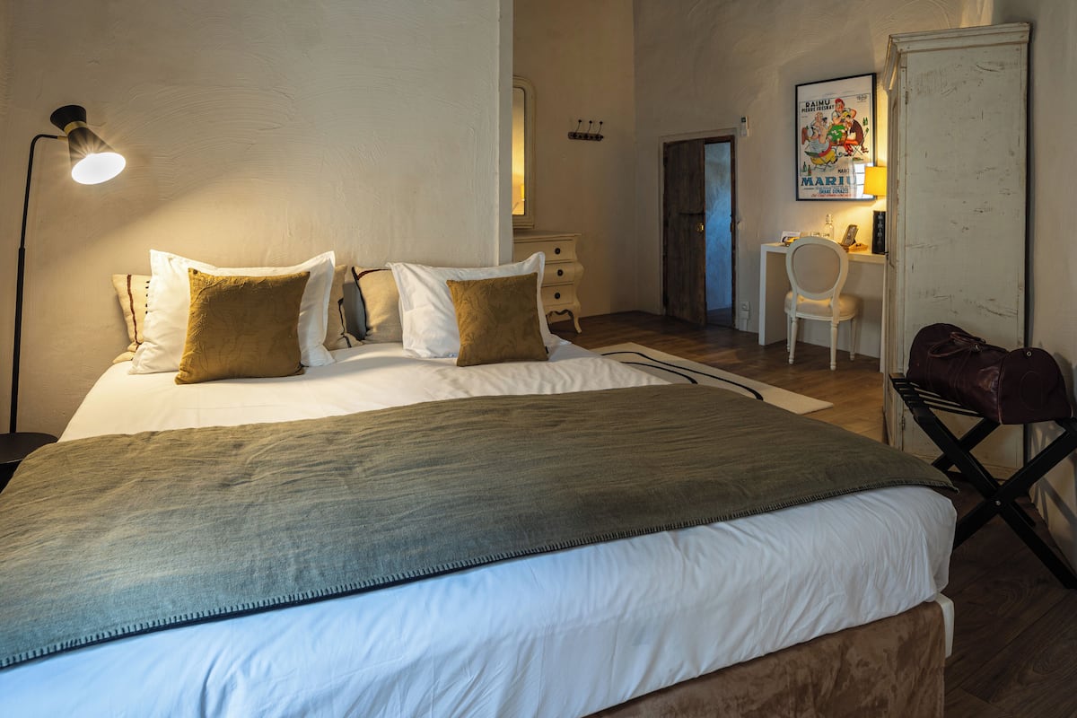 Een keurig opgemaakte slaapkamer met een bed, nachtkastjes, een bureau en een stoel.