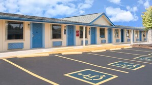 Ein Motel mit blauen Türen und Fenstern, ein Parkplatz mit Behindertenparkplätzen und einem strahlend blauen Himmel.
