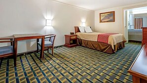 Ein Hotelzimmer mit einem Bett, einem Schreibtisch und einem Stuhl. Zwei Wandlampen und ein Bild hängen an der Wand.