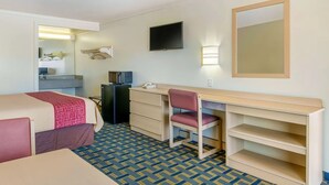 Ein Hotelzimmer mit Bett, Schreibtisch, Stuhl, Fernseher und Spiegel.