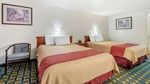 A hotel room with two beds, a chair, and two wall-mounted lamps. - Hilliard Motor Lodge (Hilliard)