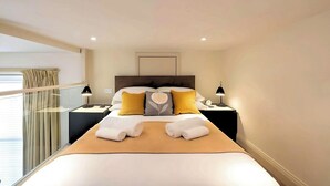 Une chambre d’hôtel avec un grand lit, deux tables de chevet avec des lampes, une fenêtre avec des rideaux et un luminaire au plafond.