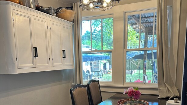 A dining area with a wooden table, chairs, and a chandelier. There is a window with a view of the outdoors. - Newly Renovated 1936 Home Close To Augusta National, Airport & Downtown! (Augusta)