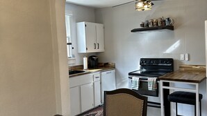 A kitchen with white cabinets, a black stove, and a ceiling fan. - Newly Renovated 1936 Home Close To Augusta National, Airport & Downtown! (Augusta)