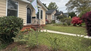 A residential house with a front porch, a mailbox, and a small garden with various plants and flowers. - Newly Renovated 1936 Home Close To Augusta National, Airport & Downtown! (Augusta)