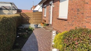 Une maison en briques avec une allée pavée, un portail en bois et un petit jardin.