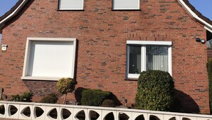 Une maison en briques rouges, dotée de deux grandes fenêtres et d’une petite fenêtre de toit.