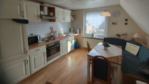 Une cuisine compacte avec des meubles blancs, une cuisinière et un coin repas comprenant une table et des chaises.