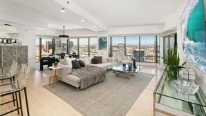 A modern living room with a large window, a sofa, a coffee table, and a glass-top dining table.