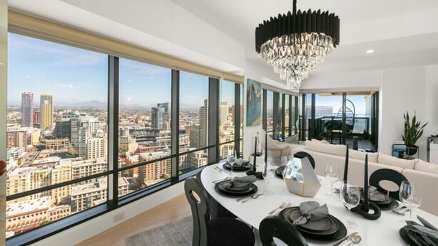 A dining area with a city view, a chandelier, and modern furnishings.