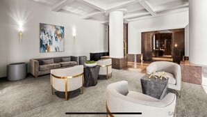 A modern lobby with a grey sofa, round coffee tables, and a large abstract painting.