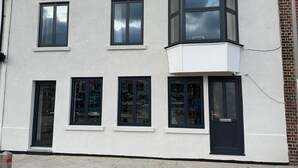 Een meerlaags gebouw met een witte gevel, meerdere ramen en een erker.