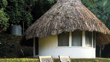 Una cabaña con techo de paja y dos bancos de madera en la entrada.