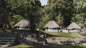 A traditional thatched-roof house with a stone staircase leading up to it, surrounded by lush greenery. - Jade Jungle Resort (Teakettle Village)