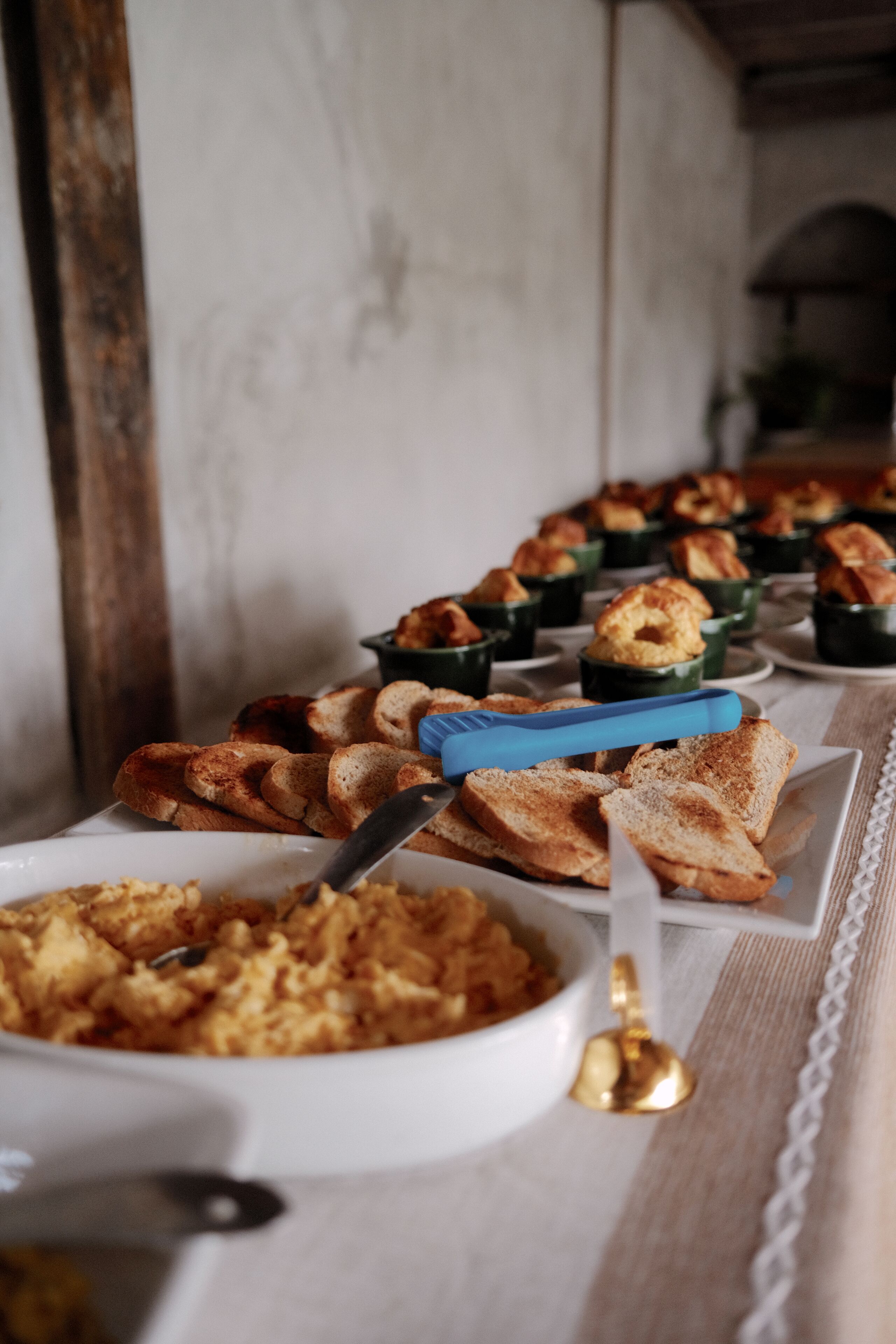 A buffet table with various dishes, including bread and a casserole, arranged on white plates and bowls.
