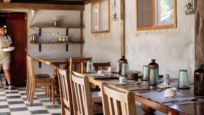A dining area with wooden tables and chairs, glassware, and shelves with jars. - Jade Jungle Resort (Teakettle Village)