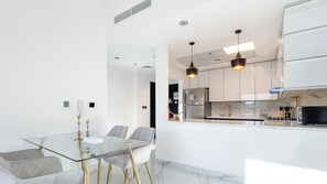 Modern kitchen with stainless steel appliances, gas stove, and glass dining table.