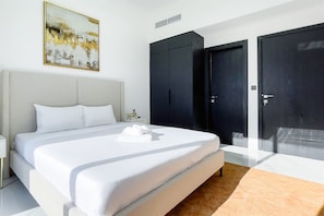 A modern bedroom with a large bed, a nightstand, a wall-mounted artwork, and a wardrobe. - Luxe Gardenia 2BR Haven in Dubai (Dubai)