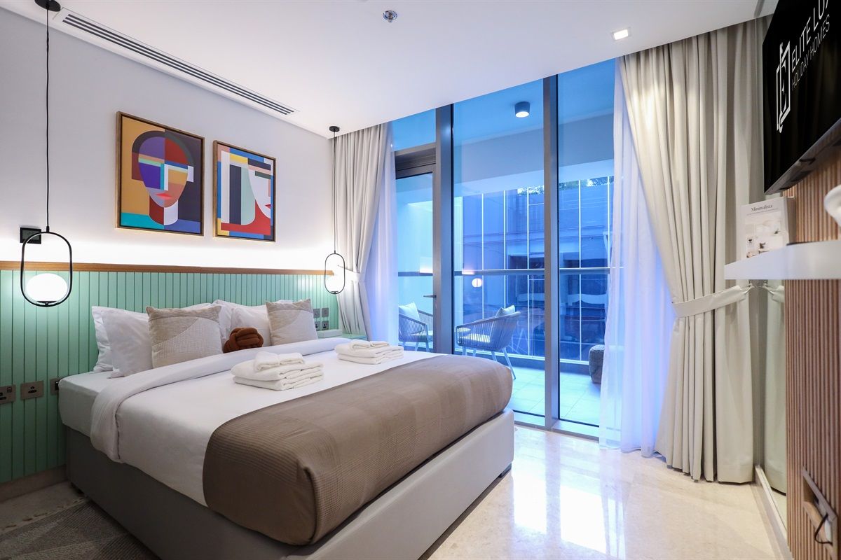 Ein modernes Hotelzimmer mit einem großen Bett, einem Balkon mit Blick und Kunstwerken an der Wand.