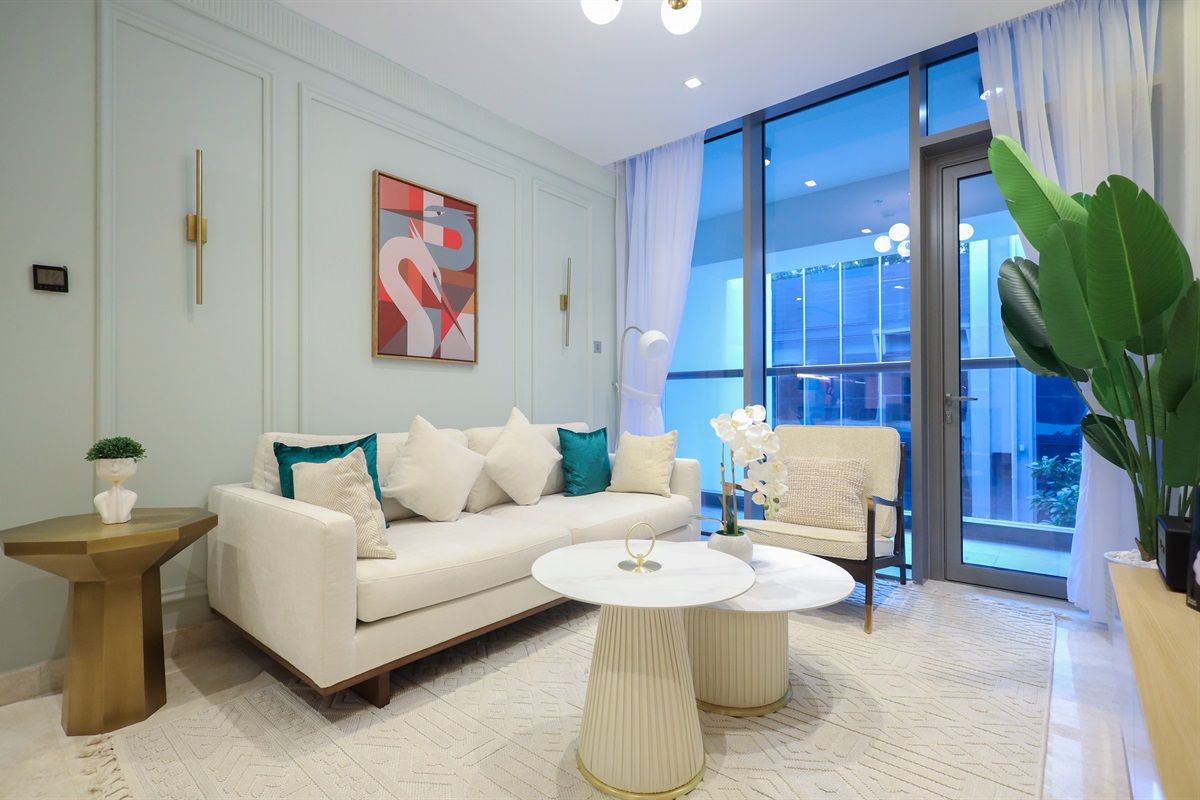 Un salon moderne avec un canapé, une table basse et un fauteuil, une grande fenêtre avec des rideaux et un tableau accroché au mur.