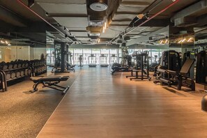 Ein Fitnessstudio mit Trainingsgeräten, einem Gewichtständer und einer Spiegelwand.