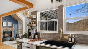 Una cocina moderna con un ventanal grande, lavavajillas integrado y una chimenea de piedra.