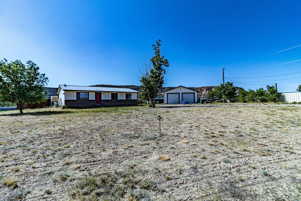 A residential area with a house, garage, and a large open field.