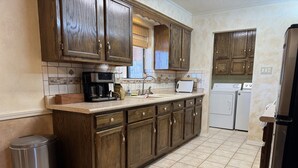 Una cocina con armarios de madera, cafetera, lavaplatos y fregadero.