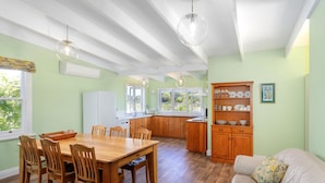 Une cuisine spacieuse avec des meubles de rangement en bois, une table à manger avec des chaises et des luminaires suspendus.