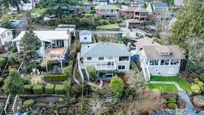 A residential area with houses, a well-maintained lawn, and a stone pathway. - Lake Washington View Home with Hot Tub BBQ Garden (Seattle)