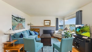 A living room with a sofa, chairs, a coffee table, a TV, and a fireplace. - Lake Washington View Home with Hot Tub BBQ Garden (Seattle)