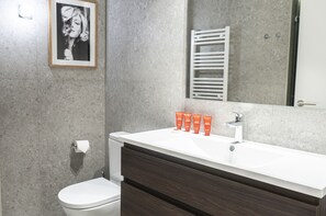 A modern bathroom with a white sink, dark wooden cabinet, and a framed picture on the wall.
