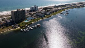An aerial view of a coastal area with a marina, buildings, and a beach. - Chateau by the Bay, Close to Restaurants and Bars, Walk to the Gulf or Bay- W209 (Pensacola Beach)
