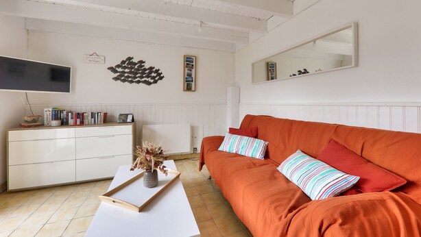A living room with a white cabinet, a flat-screen TV, a sofa with striped pillows, and a mirror on the wall. - 500m from beach, garden, 4 adults 1 child (Saint-Gildas-de-Rhuys)