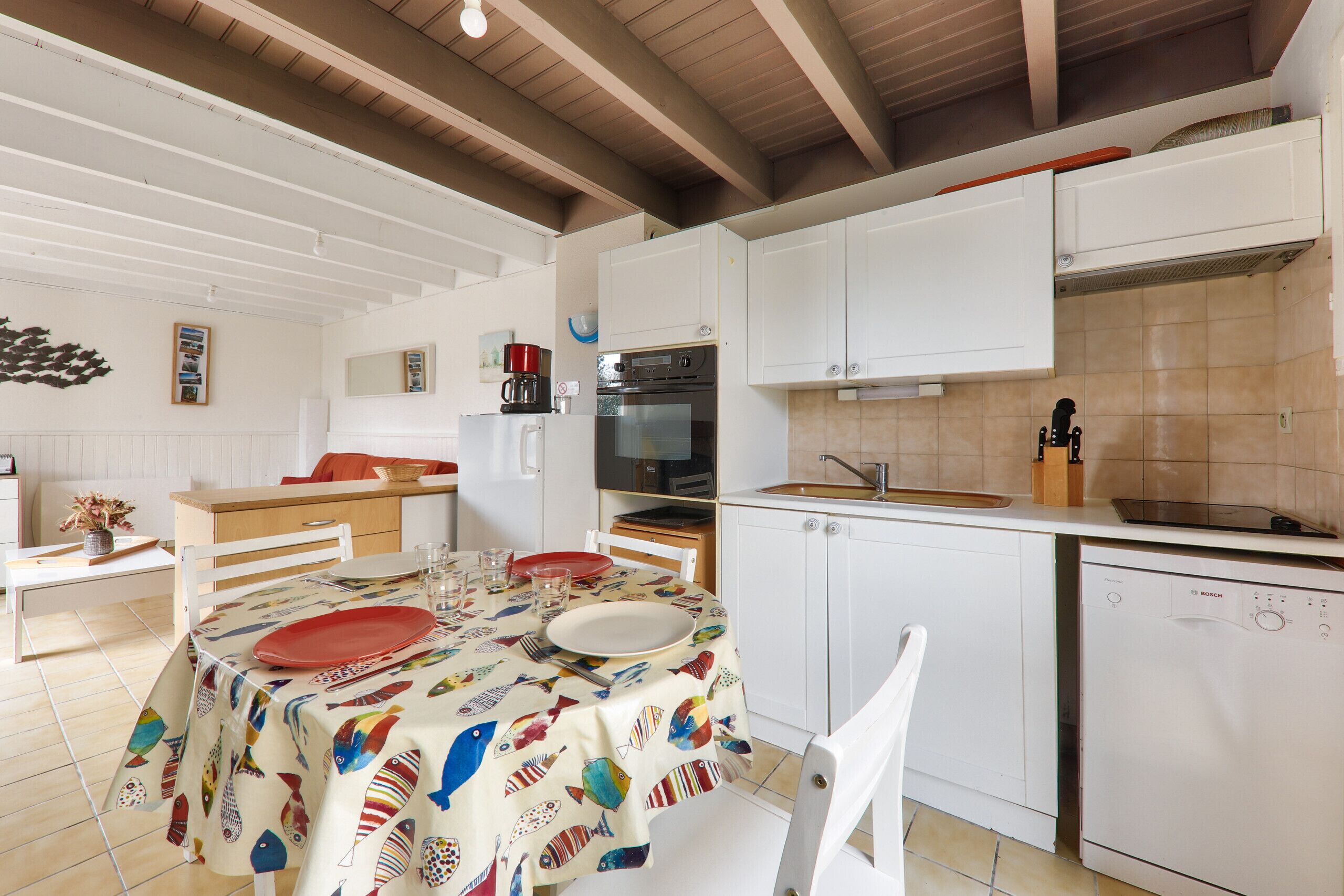 A kitchen with white cabinets, a Bosch dishwasher, and a dining area with a table set for two.