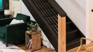 Un intérieur moderne avec un escalier, des meubles verts et une petite table d’appoint.