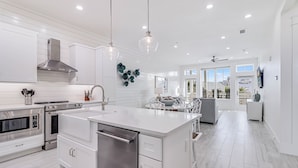 A modern kitchen with white cabinetry, stainless steel appliances, and pendant lighting. - She Sells Seashells TC 8203 (Port Aransas)