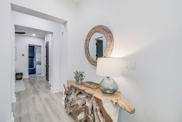 Enter a serene space with a console table, round mirror, and floor lamp.