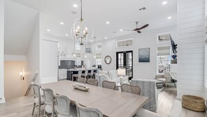 A spacious dining area with a long table, wicker chairs, and a chandelier. - Sandy Cheeks 409 COA (Port Aransas)
