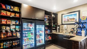 Un espace de libre-service proposant des boissons, avec une machine à café, un réfrigérateur rempli d’en-cas et une enseigne « My Coffee Place ».