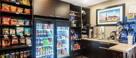 A self-service beverage station with a coffee machine, a refrigerator stocked with snacks, and a My Coffee Place sign.