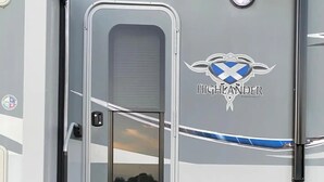 A travel trailer with a sliding door, a logo, and a ramp leading to the entrance. - Sunniland Ranch Airport 08FD Fly-In Destination

 (Okeechobee)