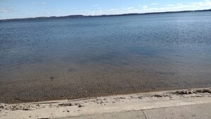 A clear view of a beach with calm water and a distant shoreline. -  House Lakefront Beautiful Sleeps 12 AC, Wi Fi, 38 minutes to GB (Shawano)