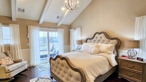 A spacious bedroom with a large bed, a chair, a nightstand, and a view of the outside. - 4-bedroom vacation home steps to Seaside Heights Boardwalk (Seaside Heights)