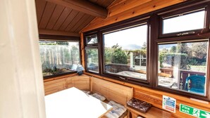 Una cabaña acogedora con interior de madera, ventanas amplias, una mesita y un letrero de salida de incendios.