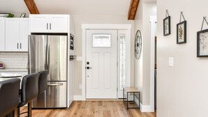 A modern kitchen with white cabinets, a stainless steel refrigerator, and a wooden ceiling.