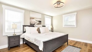 A bedroom with a bed, nightstands, a lamp, and a ceiling light fixture.