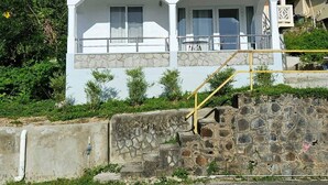 Ein zweistöckiges Gebäude mit Balkon, Steinfassade und einer kleinen Treppe, die zum oberen Stock führt.